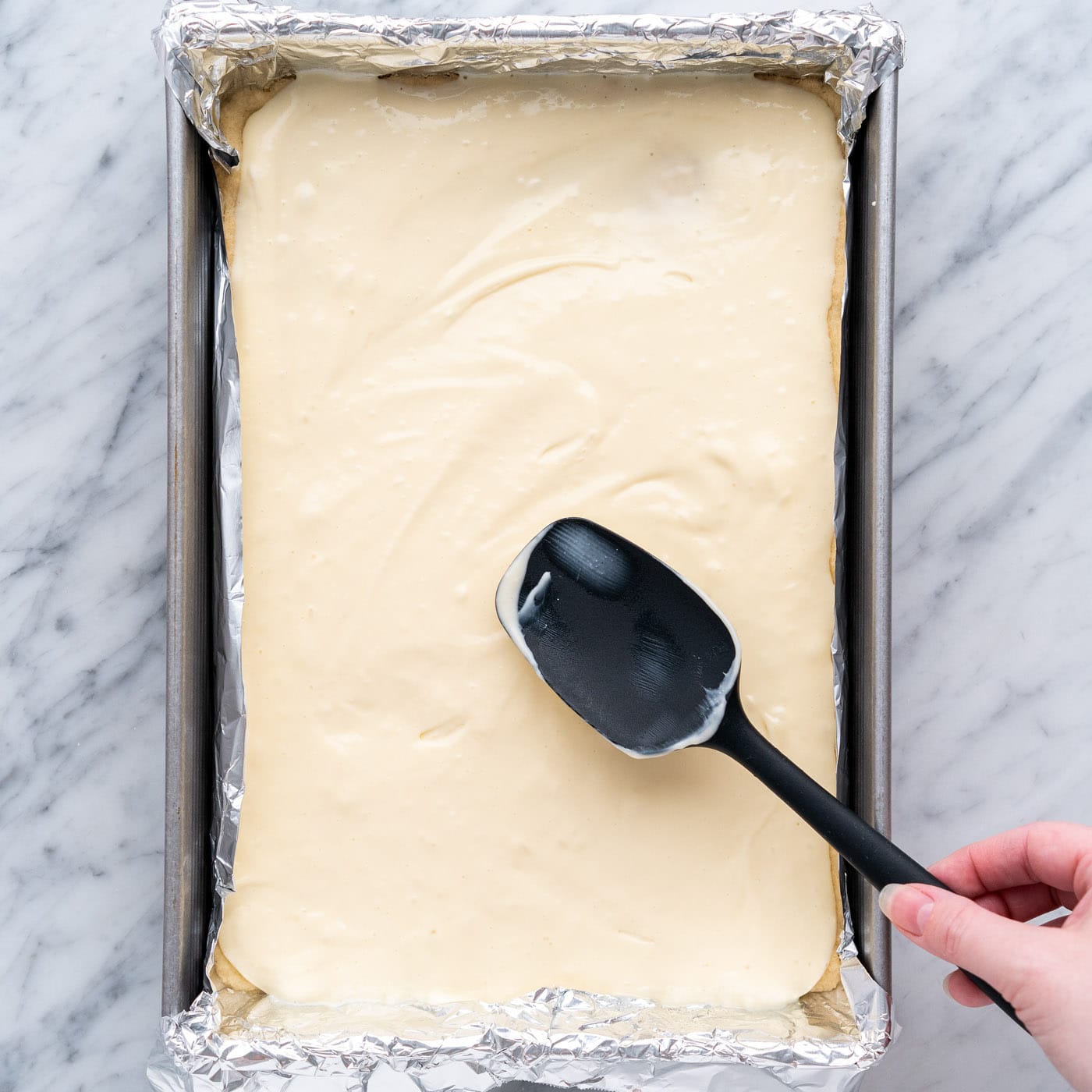 spreading cheesecake mixture over shortbread crust