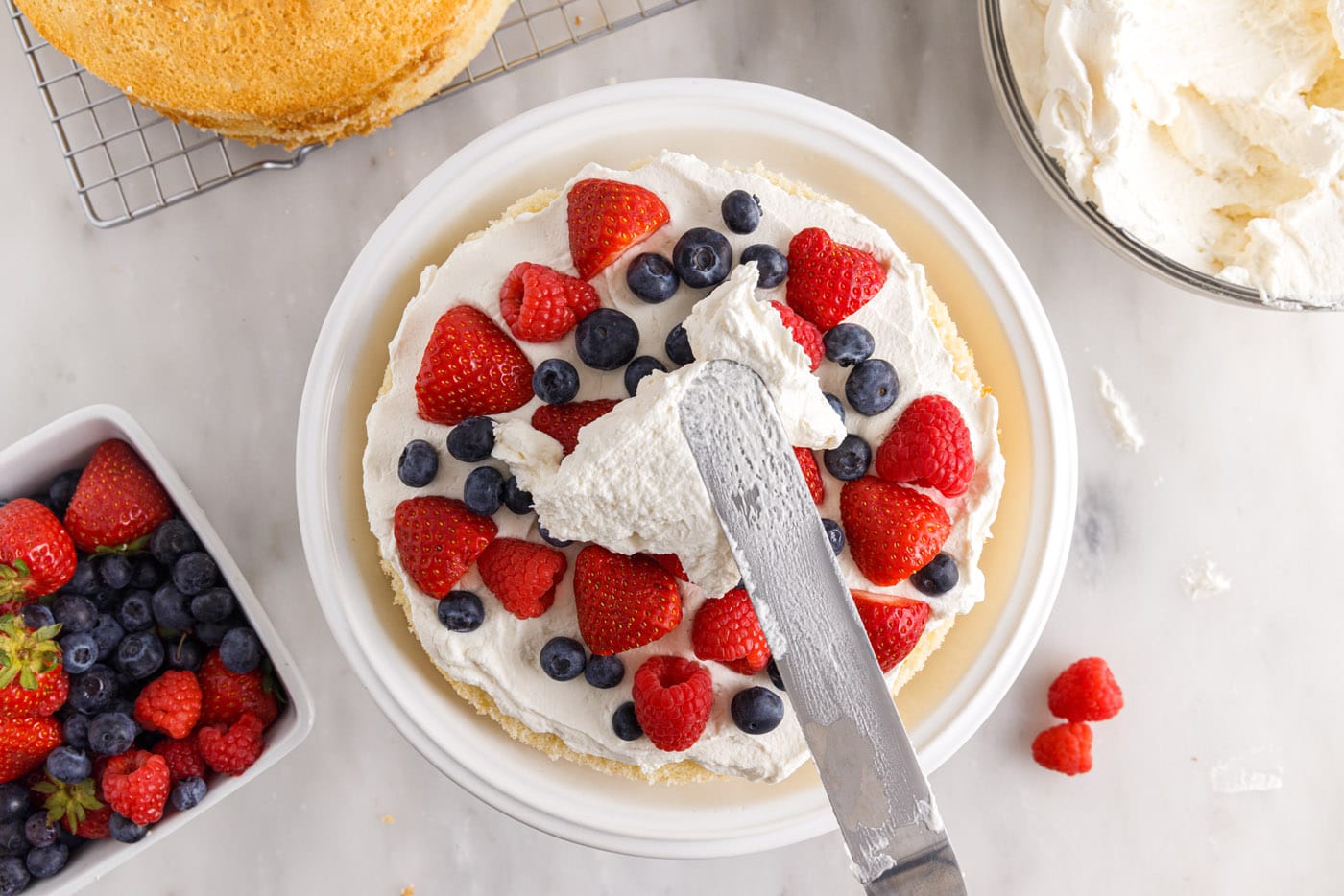 spreading chantilly frosting on top of fresh berries