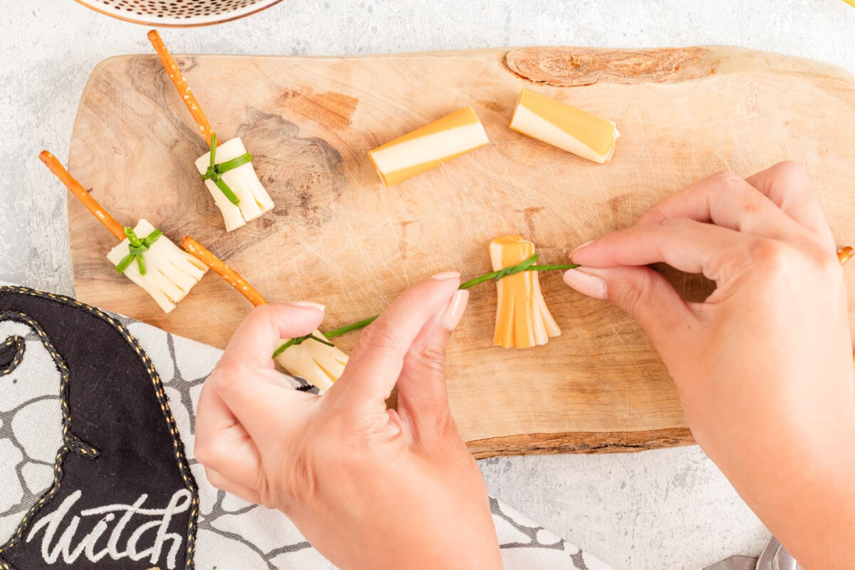 tying chive around cheese broomstick