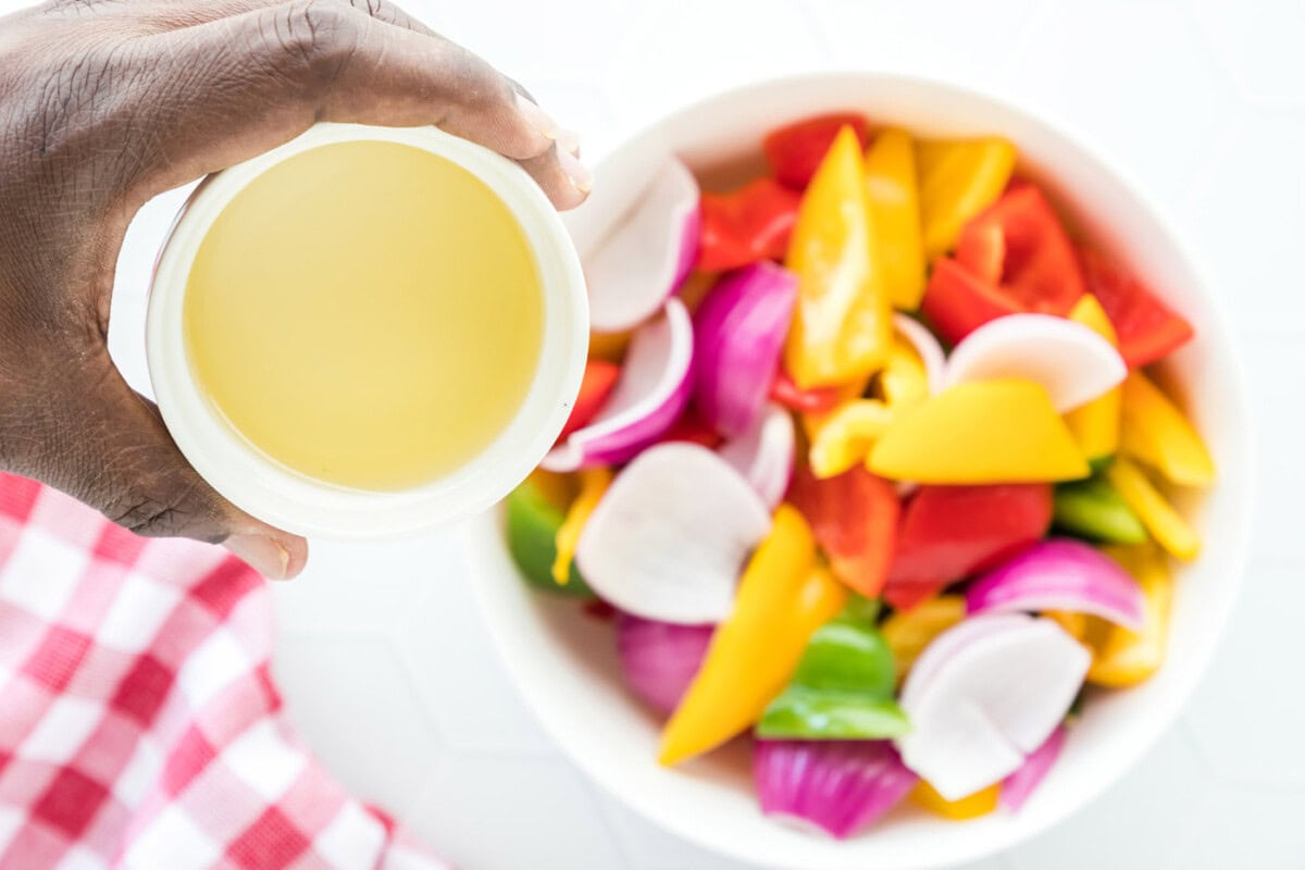 pouring oil over fresh cut veggies