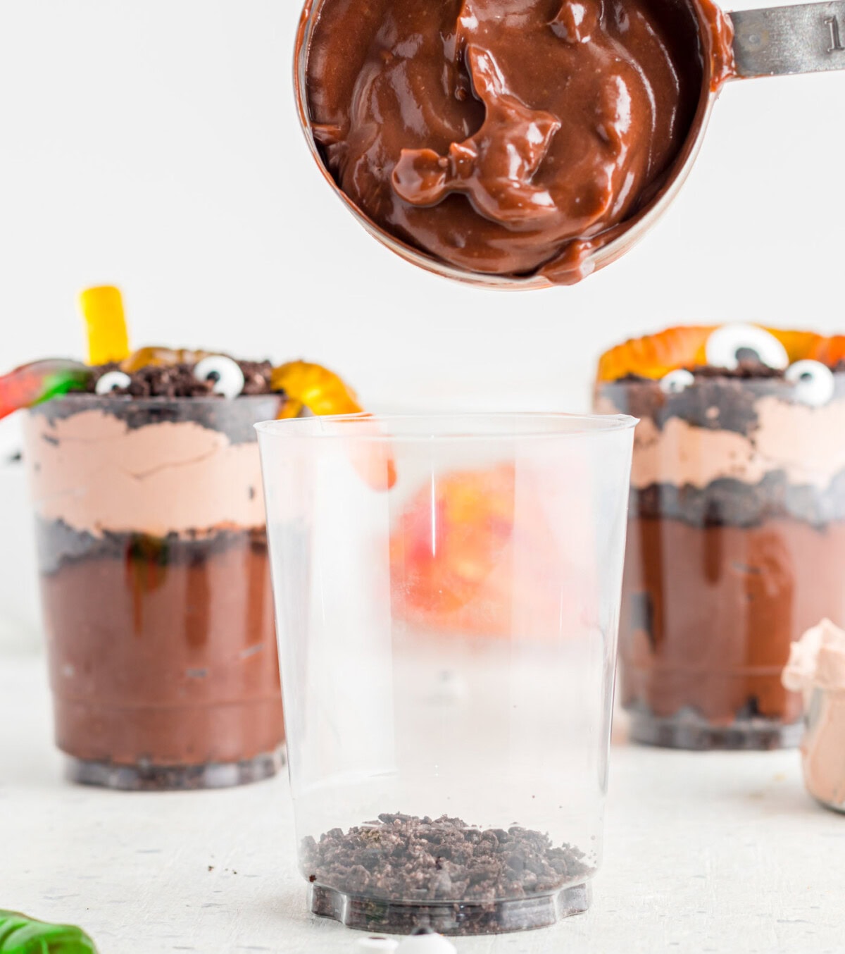 adding chocolate pudding to dirt cups