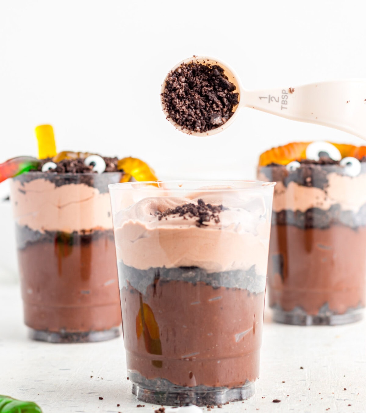 adding oreo cookie crumbs to the top of halloween dirt cups