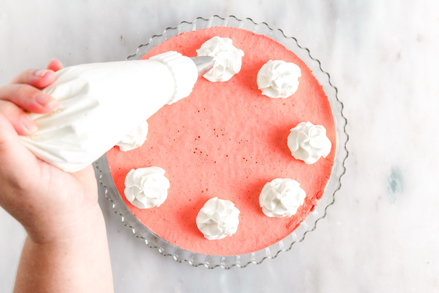 piping whipped cream on top of layered jello pie