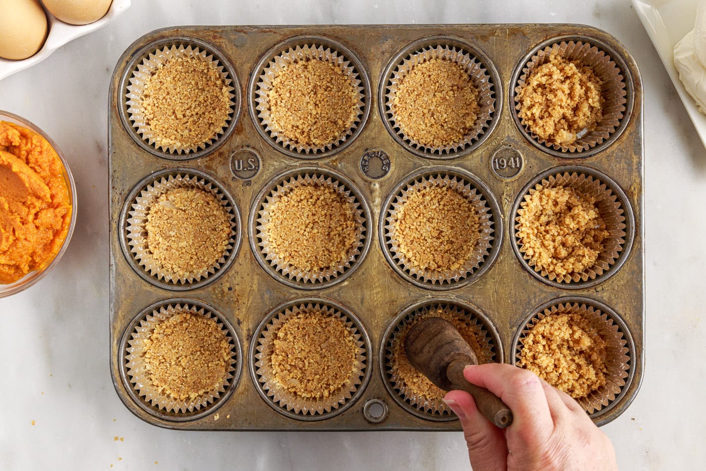 pressing graham cracker crust into a muffin tin