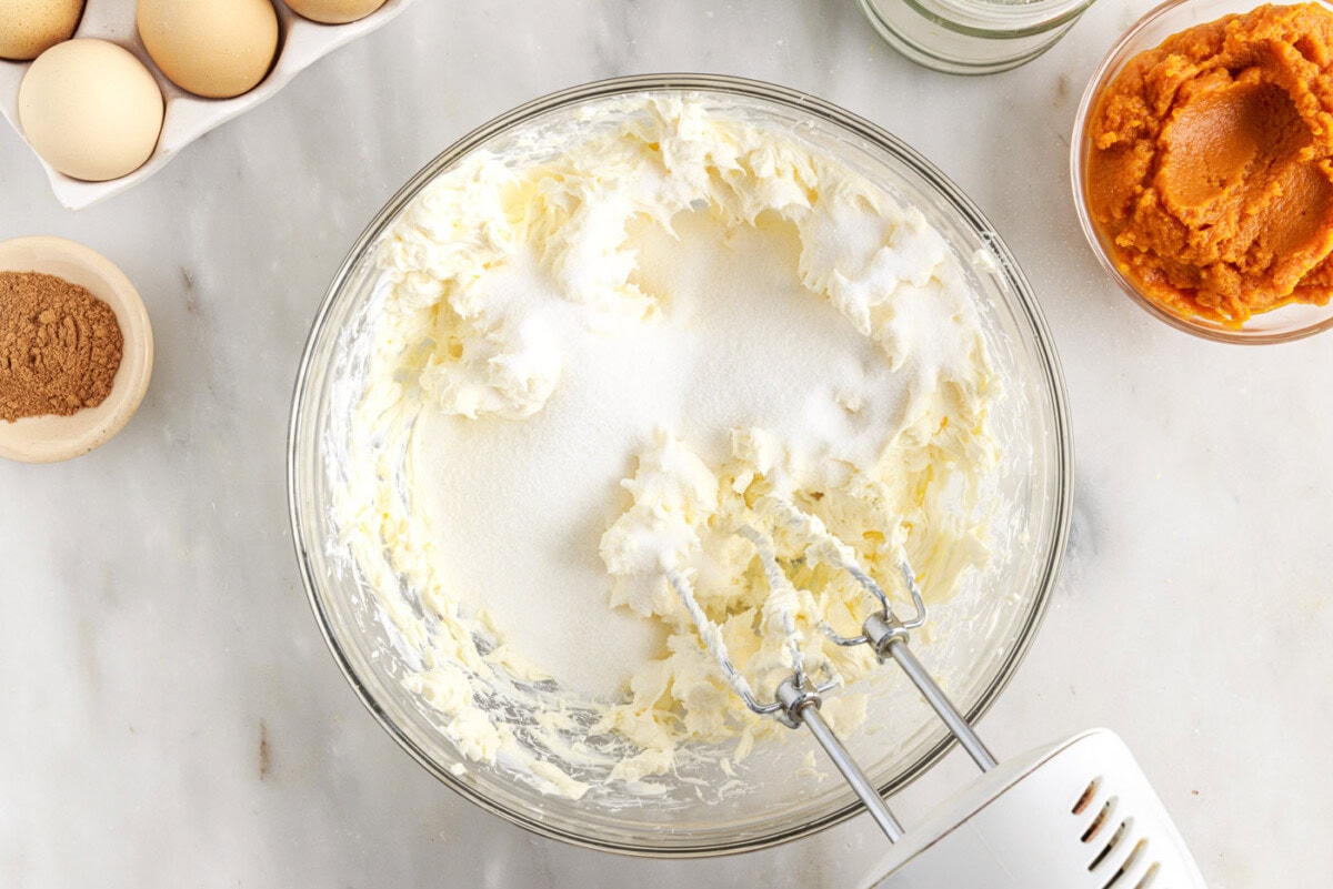 beating cream cheese with sugar in a bowl