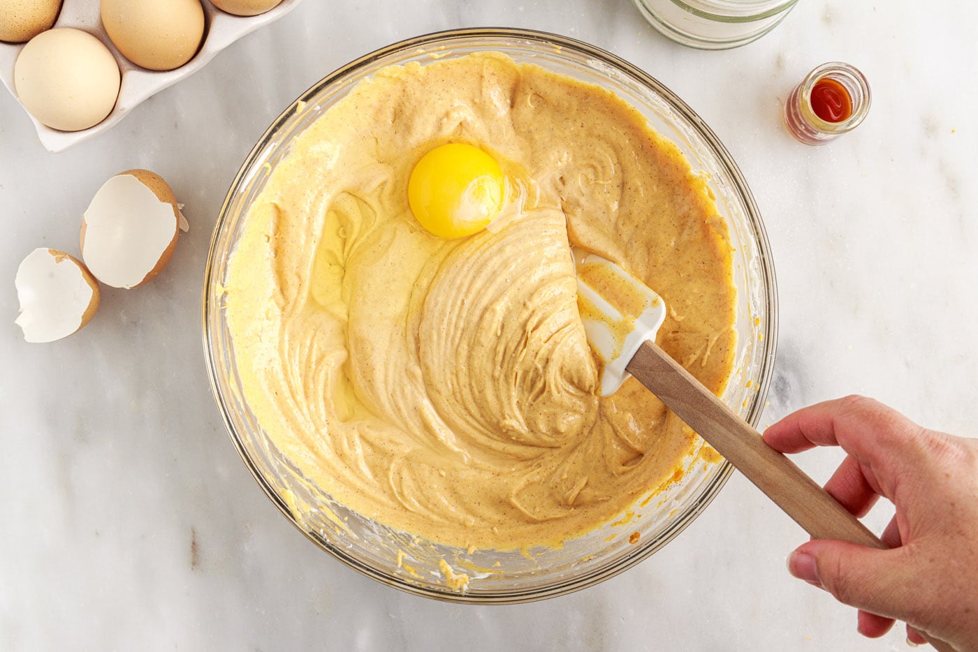 mixing eggs into pumpkin cheesecake filling