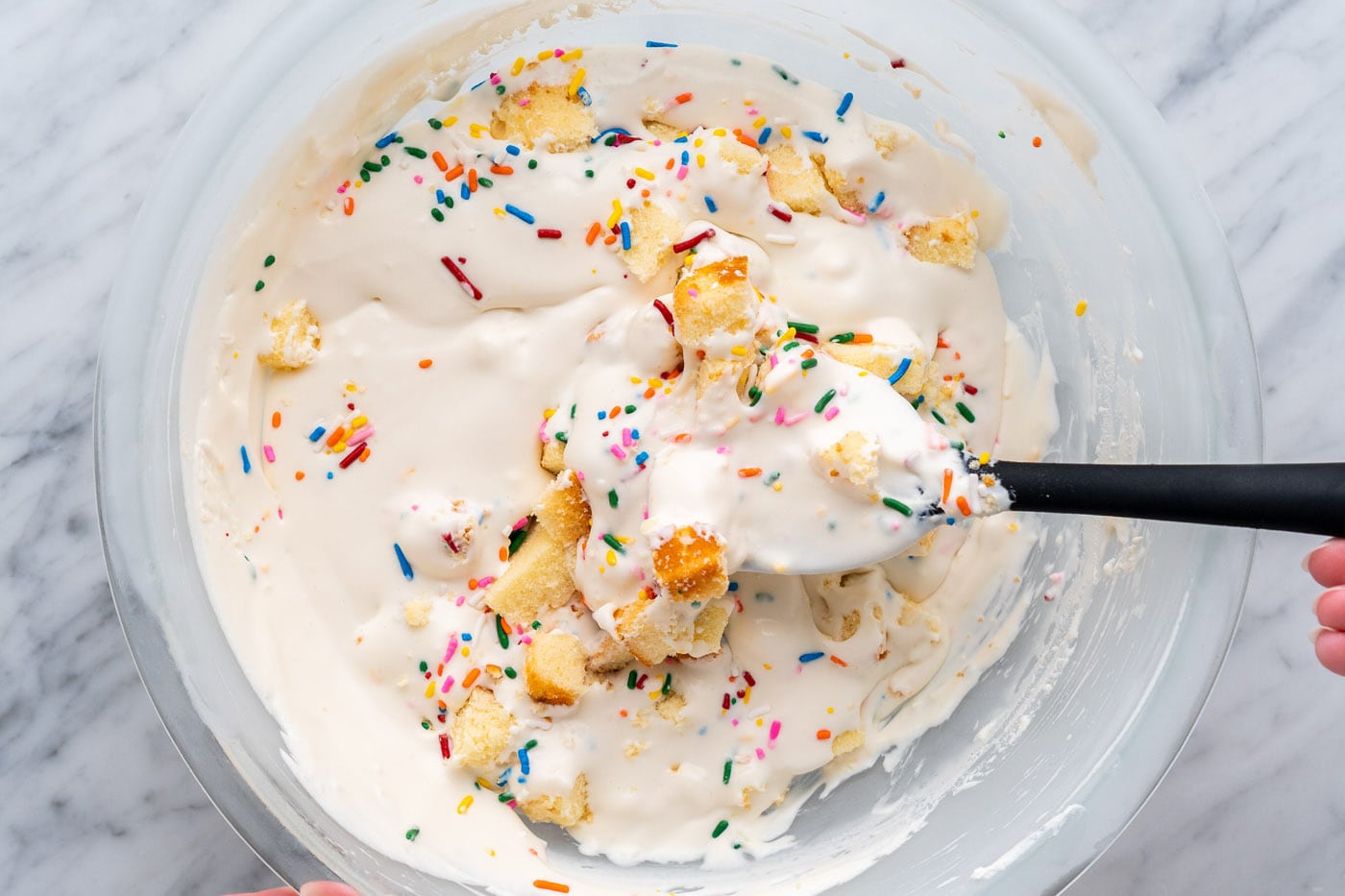 mixing no churn birthday cake ice cream in a bowl