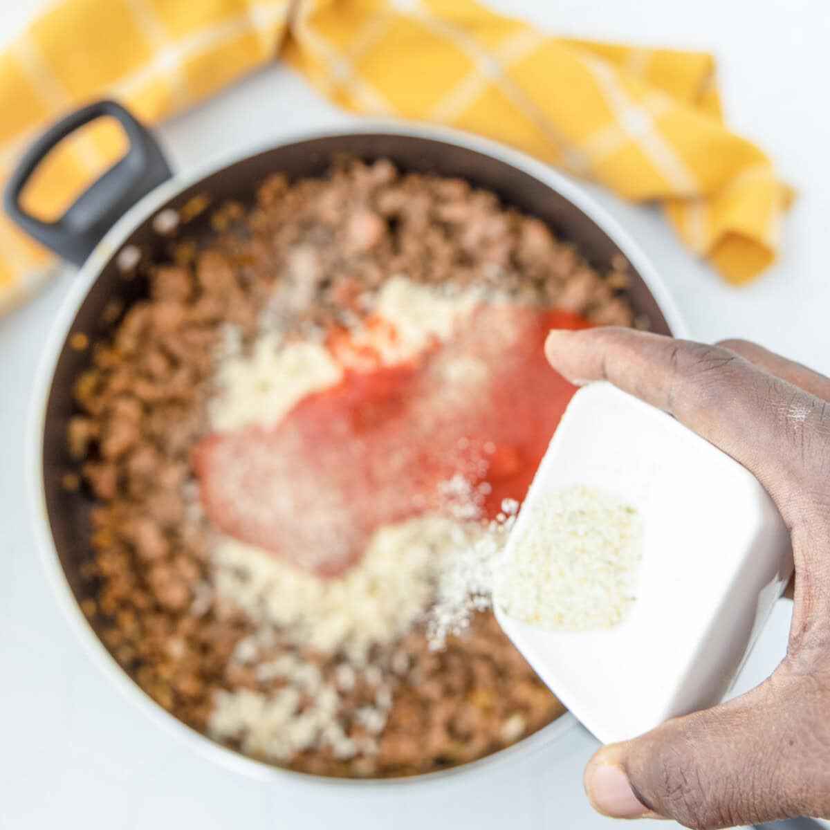 pouring garlic salt over meat mixture in skillet