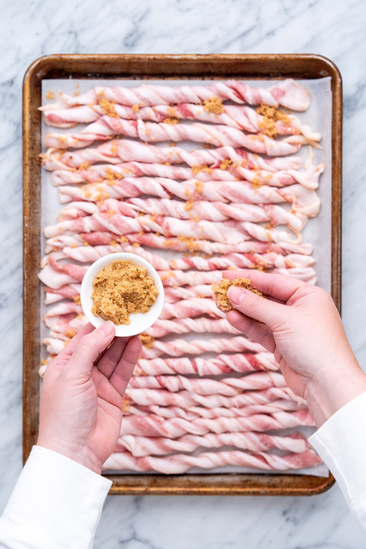 sprinkling brown sugar over twisted bacon