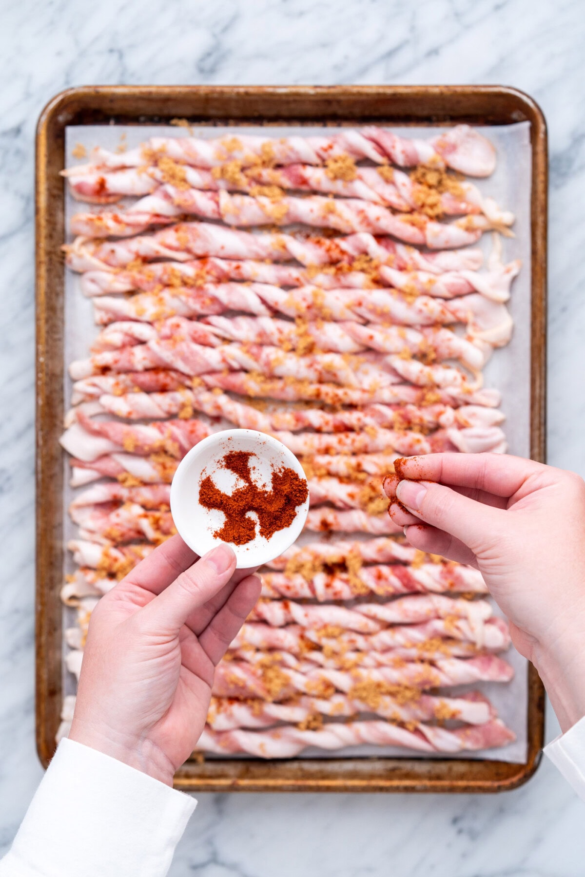 sprinkling cayenne pepper onto bacon twists
