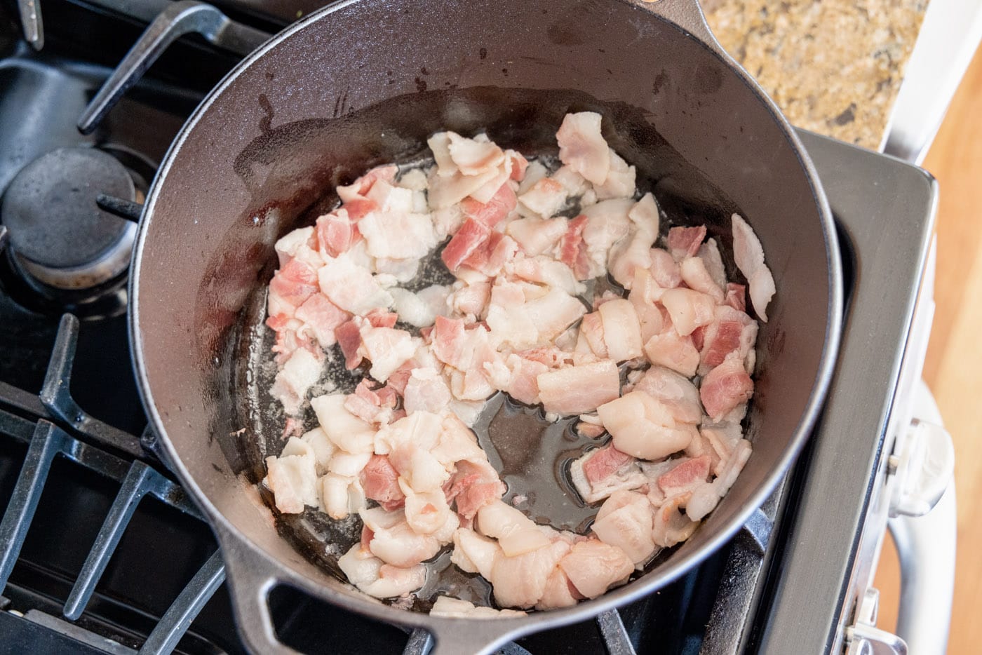 bacon cooking in a dutch oven with oil