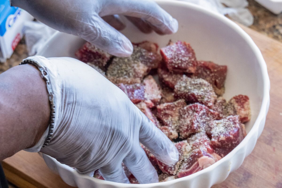 tossing cubed beef with seasonings in a bowl