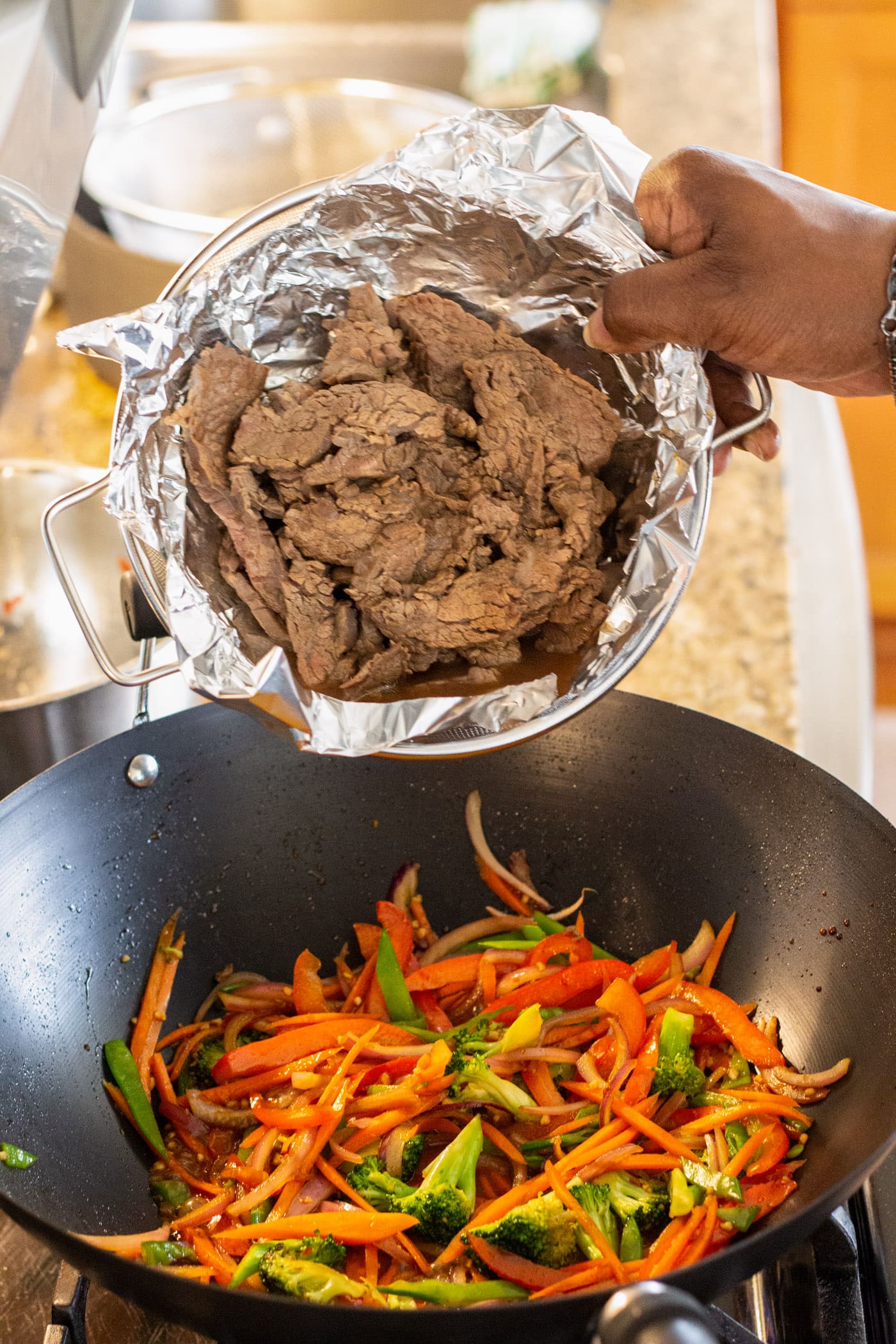 adding beef to wok with veggies