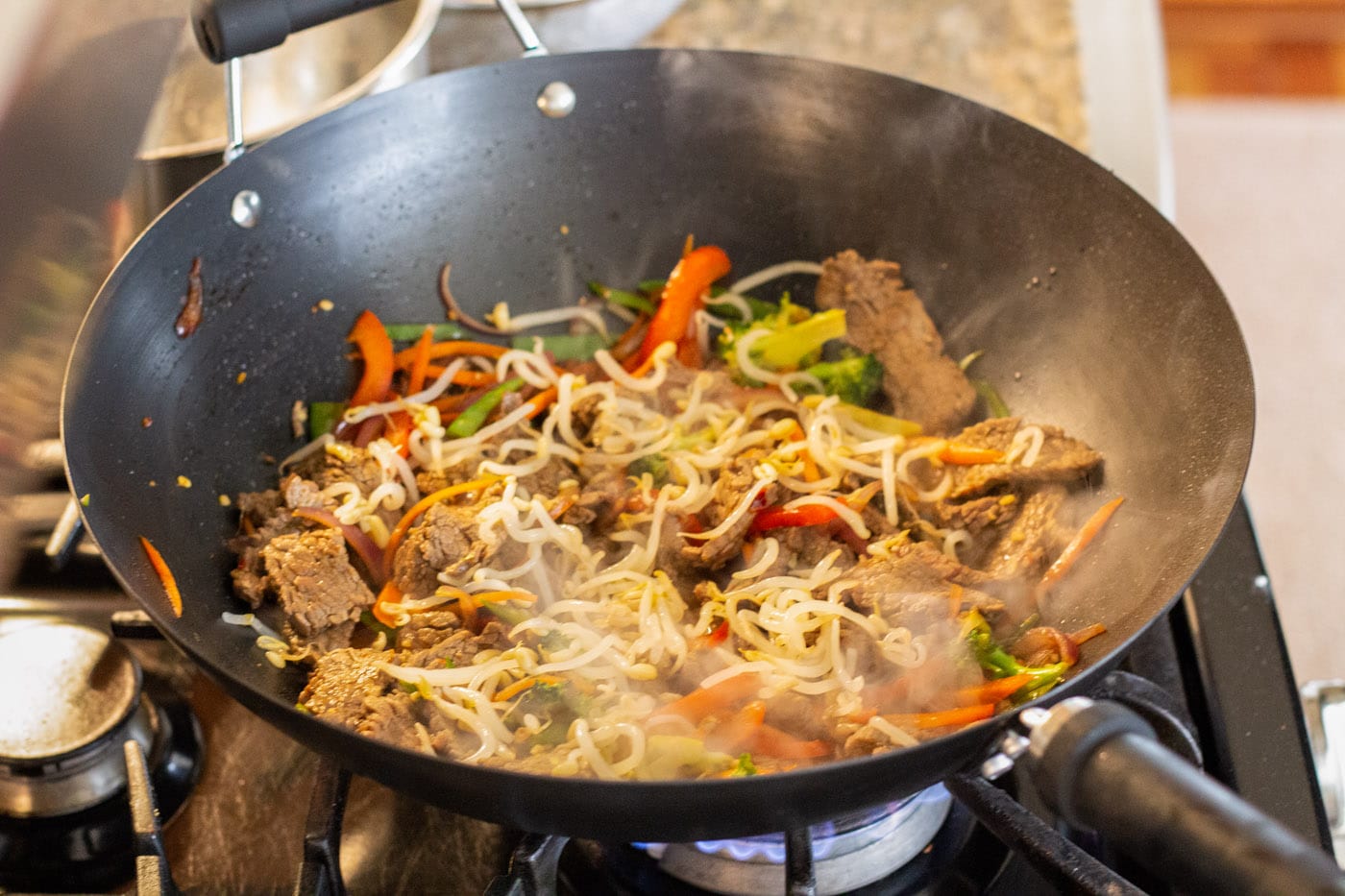 bean sprouts added to beef lo mein in a wok