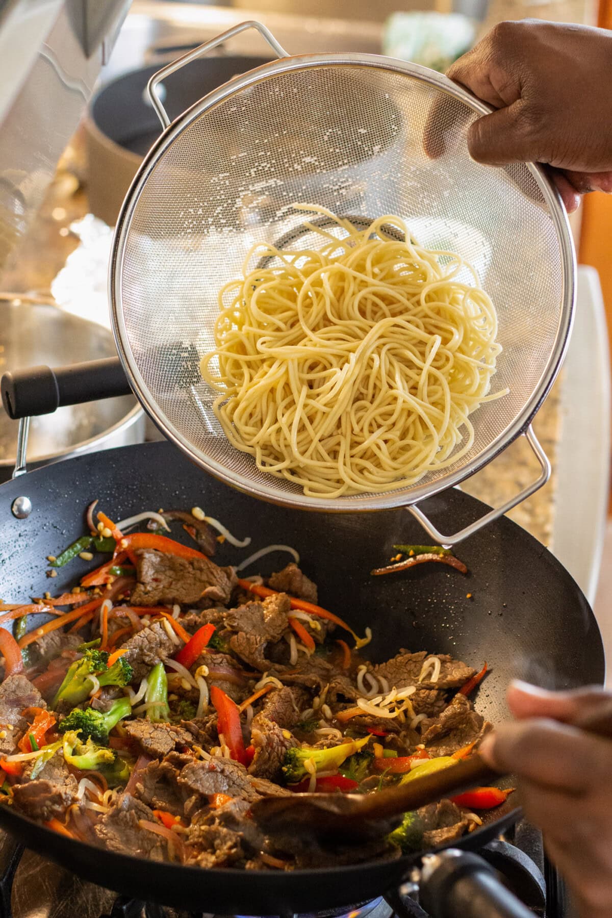 adding lo mein noodles to stir fry