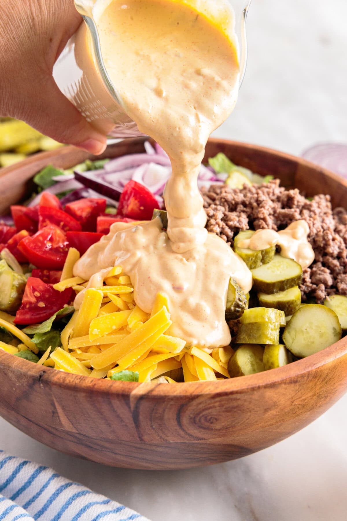 pouring big mac sauce over salad