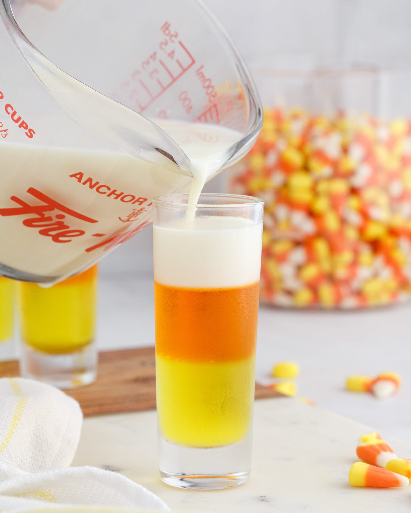 pouring condensed milk gelatin on top of candy corn jello shots