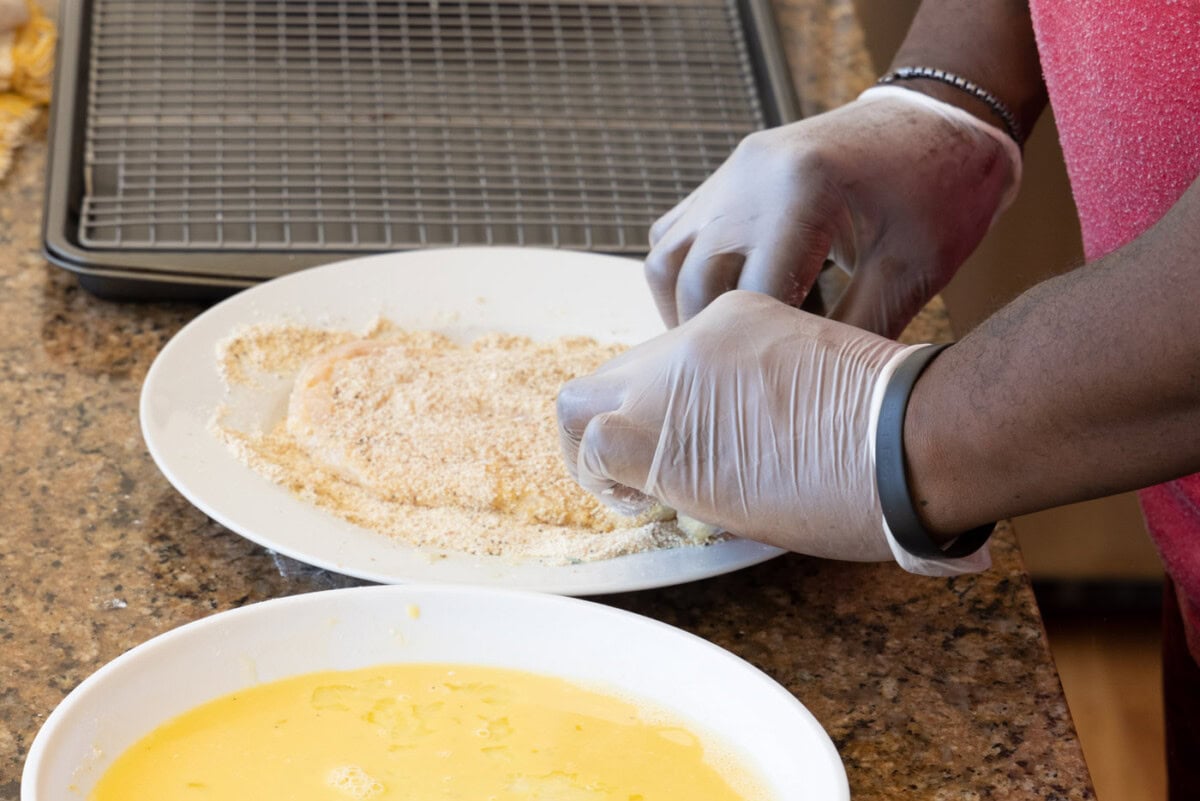 laying chicken cutlet in breadcrumb mixture