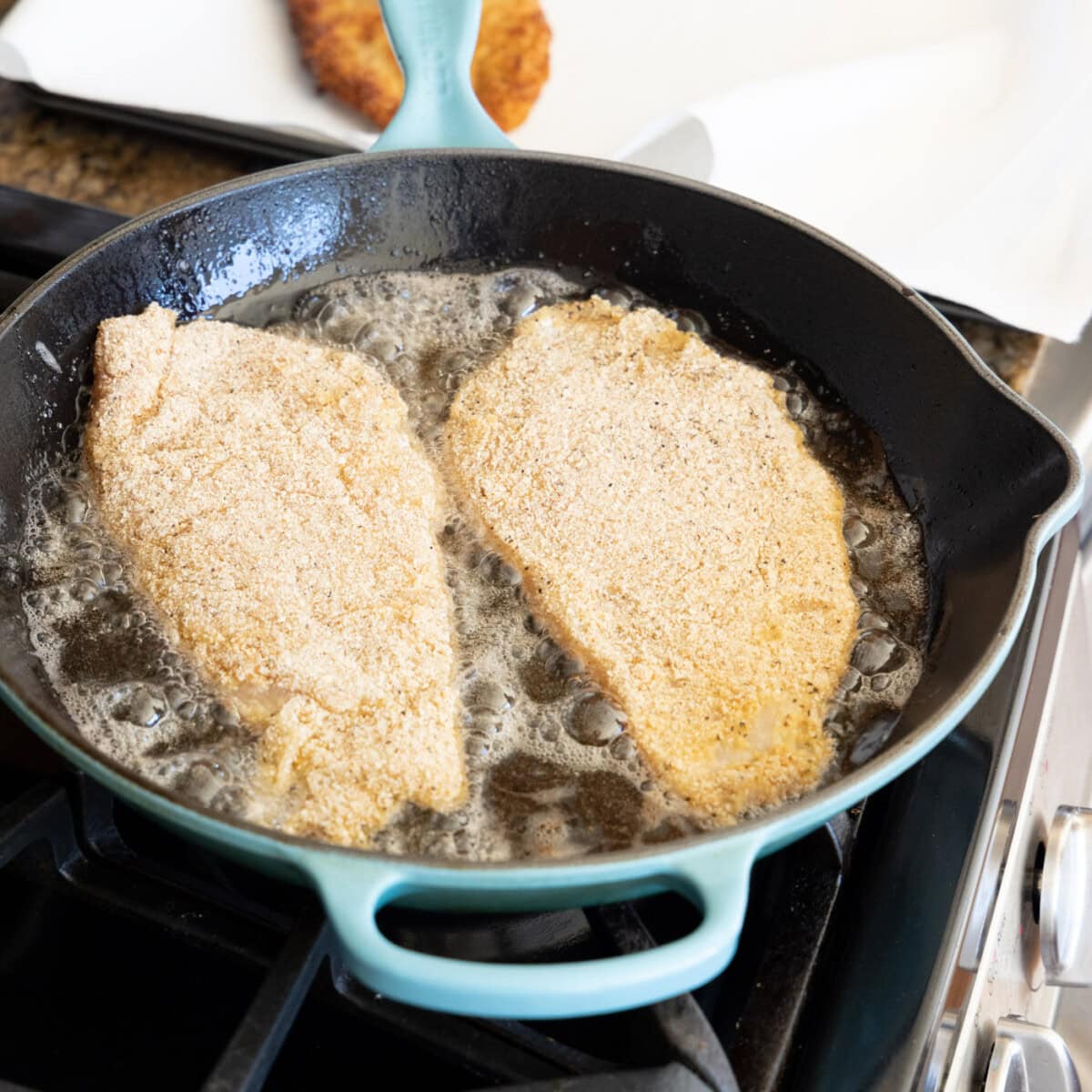 chicken cutlets in a skillet with oil