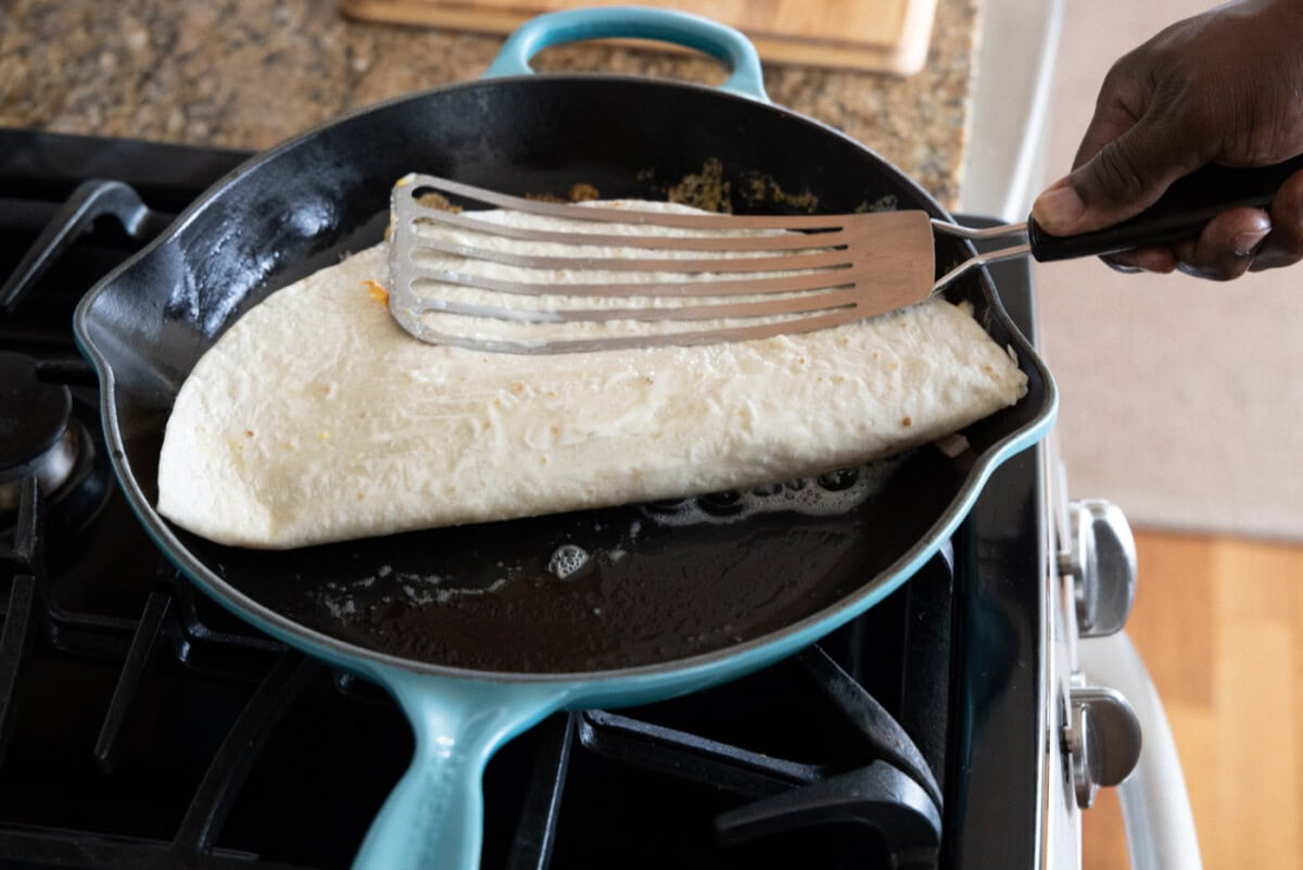 pressing chicken quesadilla into skillet