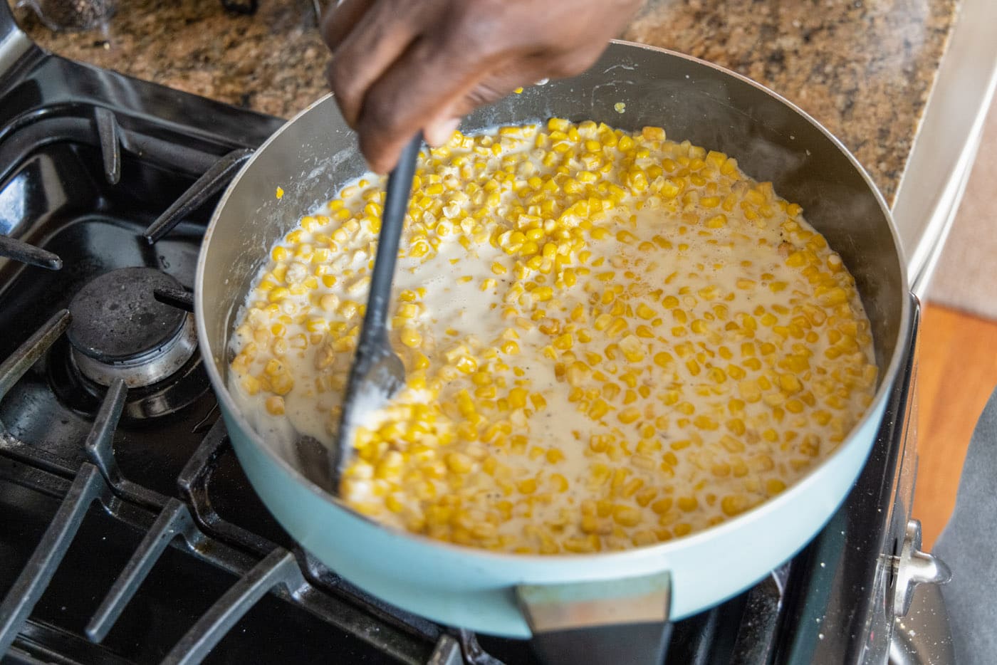 stirring creamed corn in a skillet