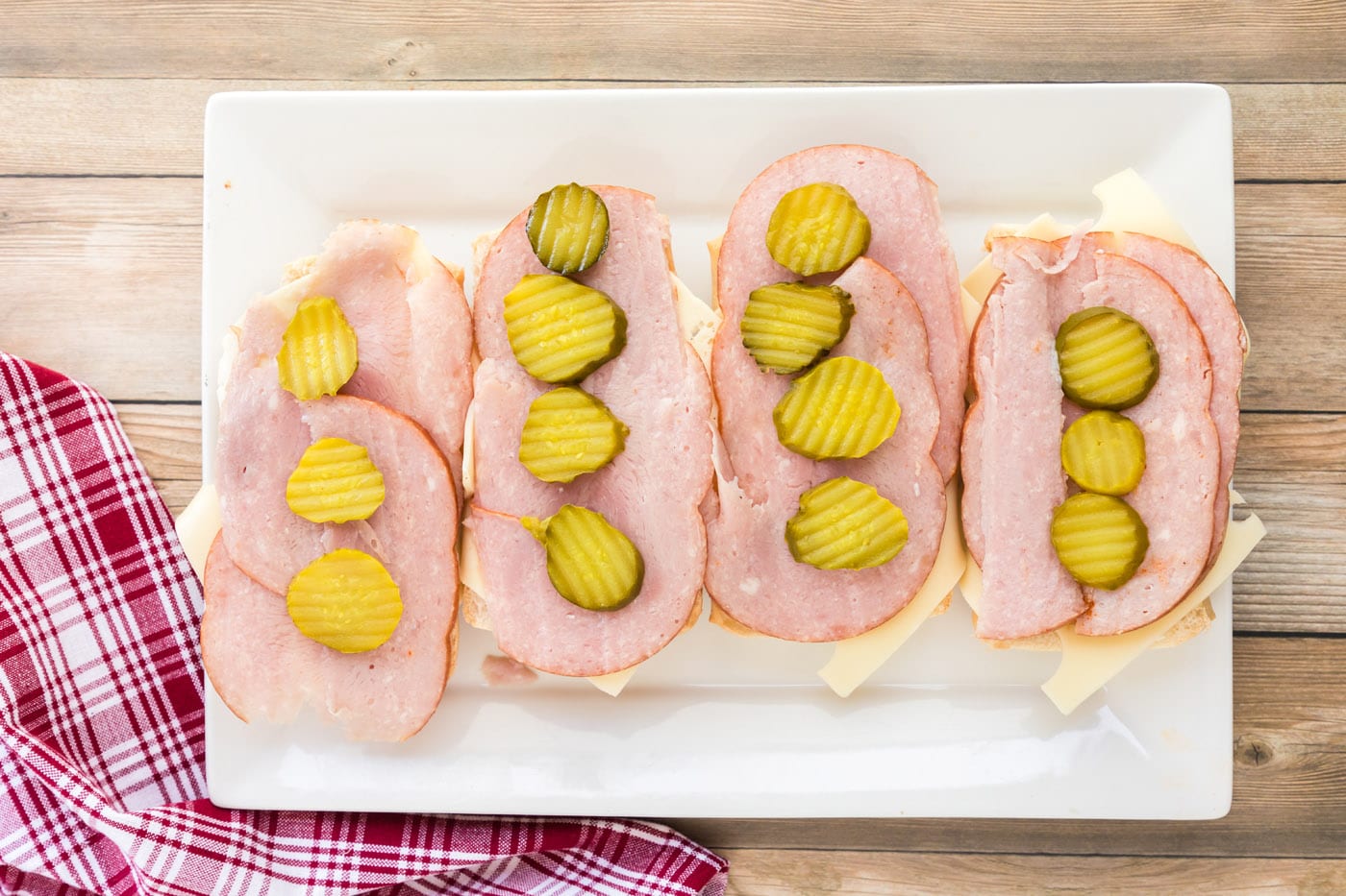 Pickle rounds on top of ham and Swiss cheese for Cubano