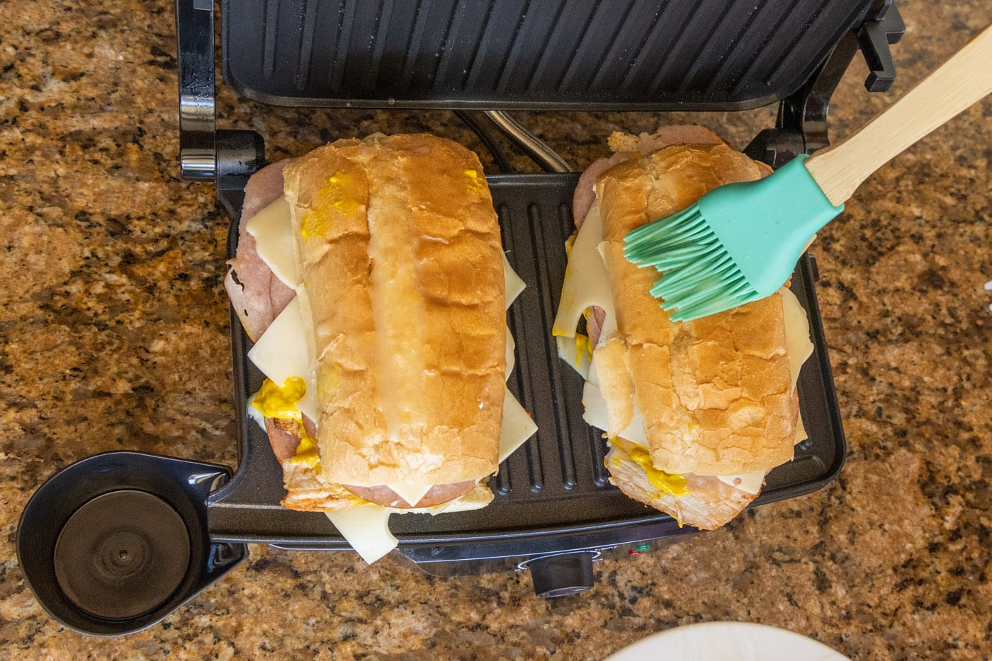 brushing the top of Cuban sandwich with butter