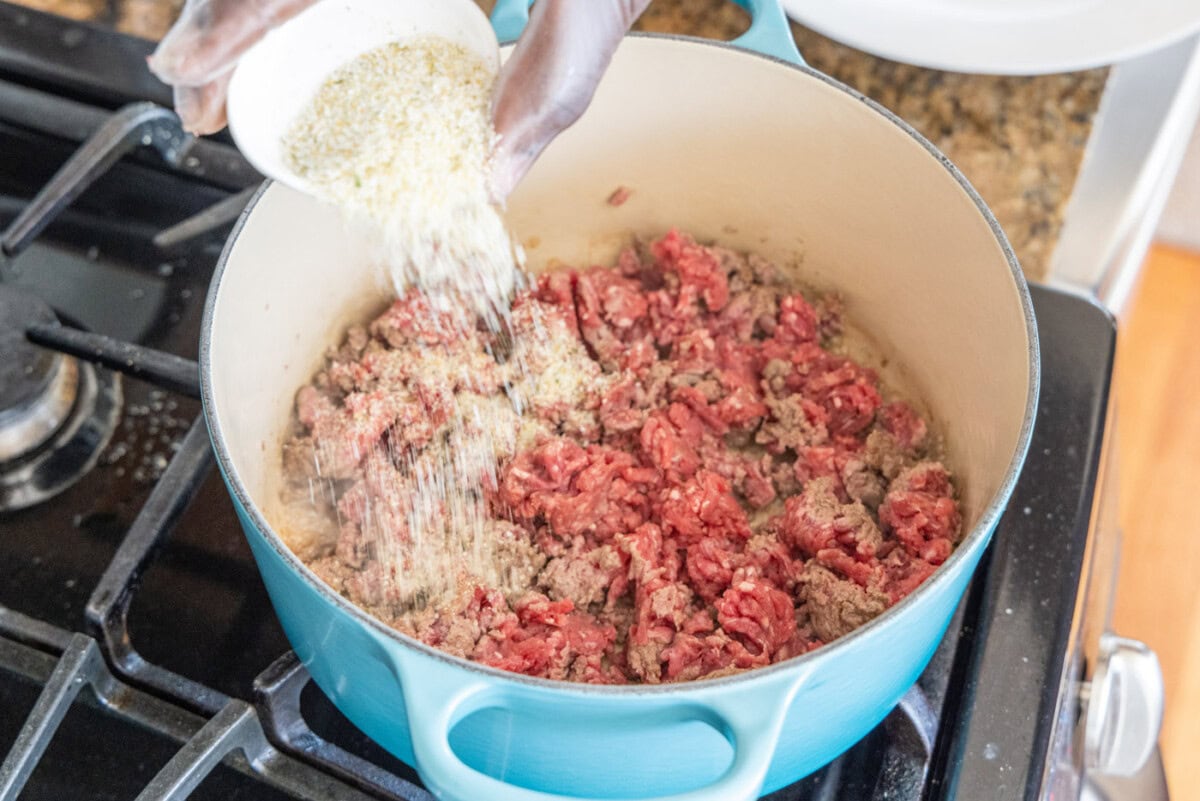 adding garlic salt to dutch oven with ground beef