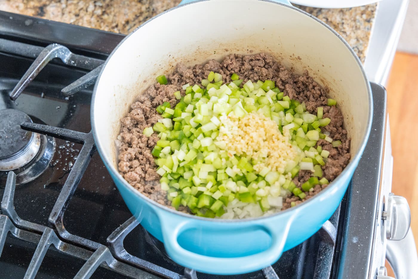 minced garlic added to dutch oven of ground beef, celery, onion, and peppers