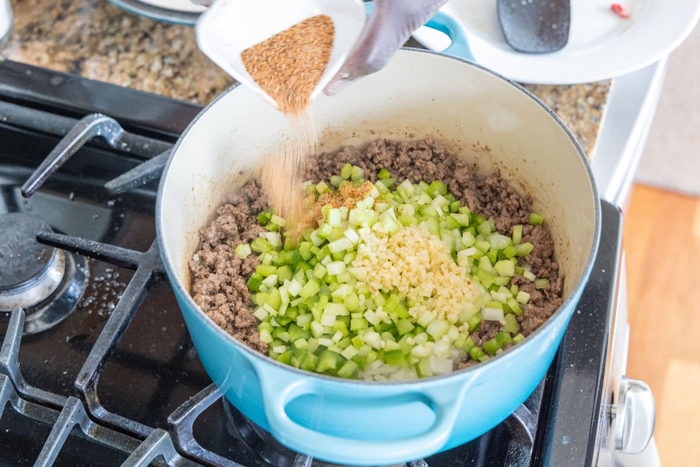 adding cajun seasoning to dirty rice mixture in a dutch oven
