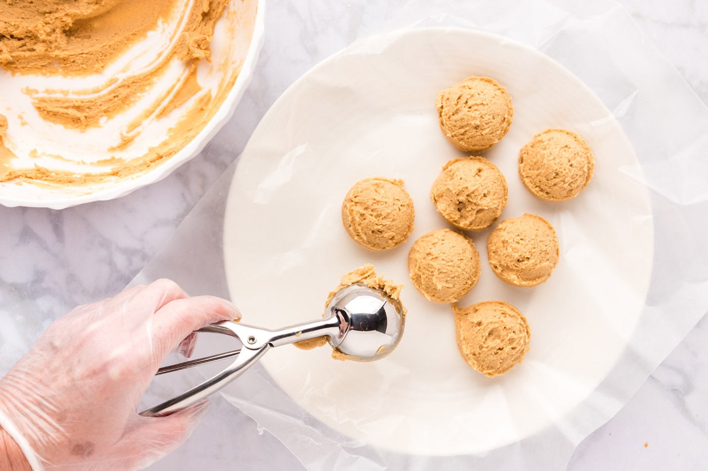 scooping peanut butter cookie dough into balls on a plate
