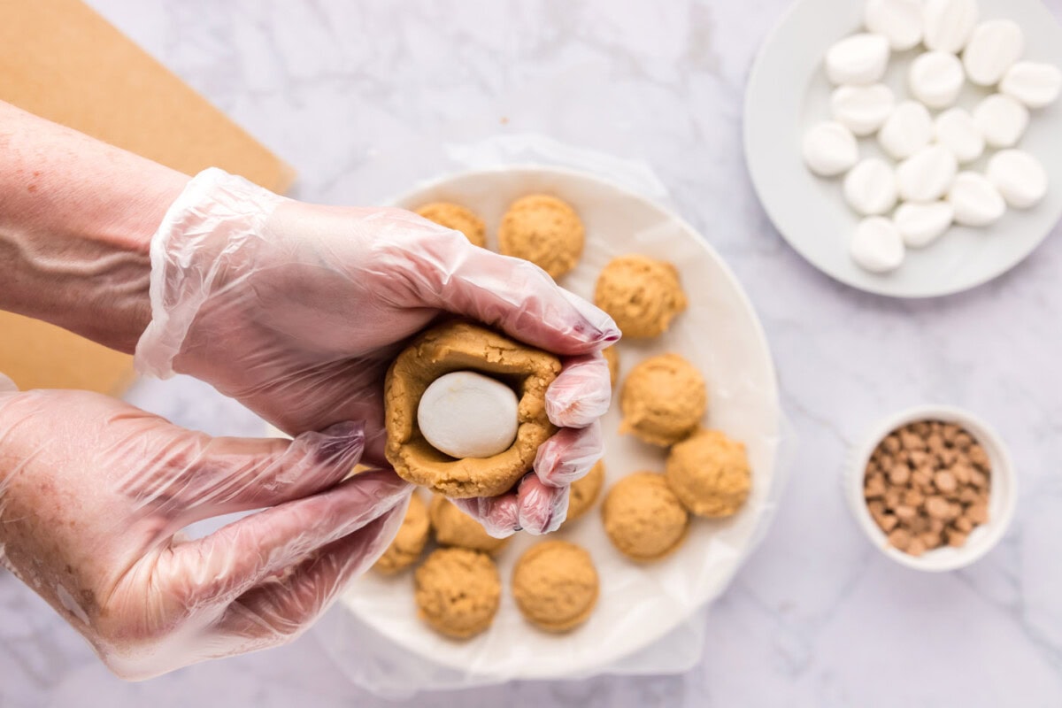 squeezing cookie dough over marshmallows