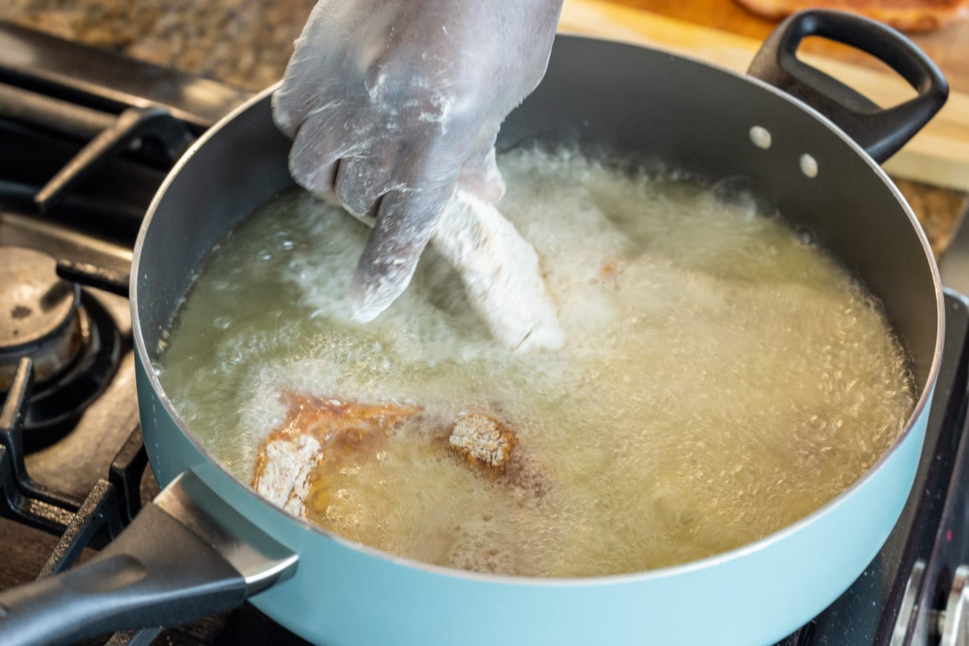 placing pork chop into a skillet with hot oil