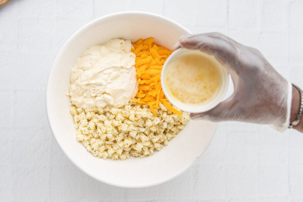 potatoes, cream of chicken mixture, and cheese in a bowl