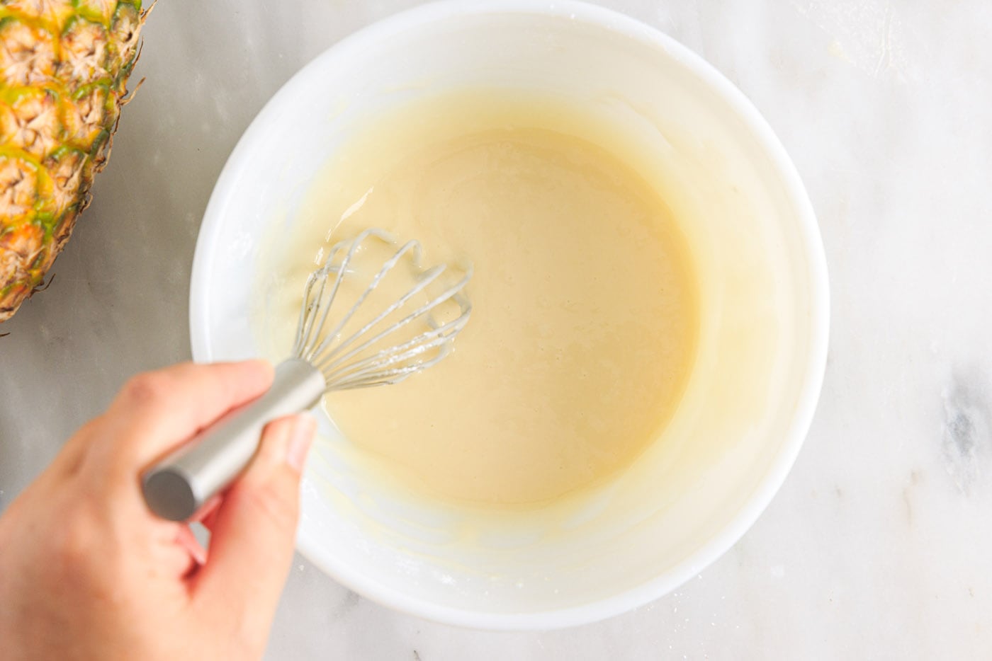 whisking pineapple glaze in a bowl