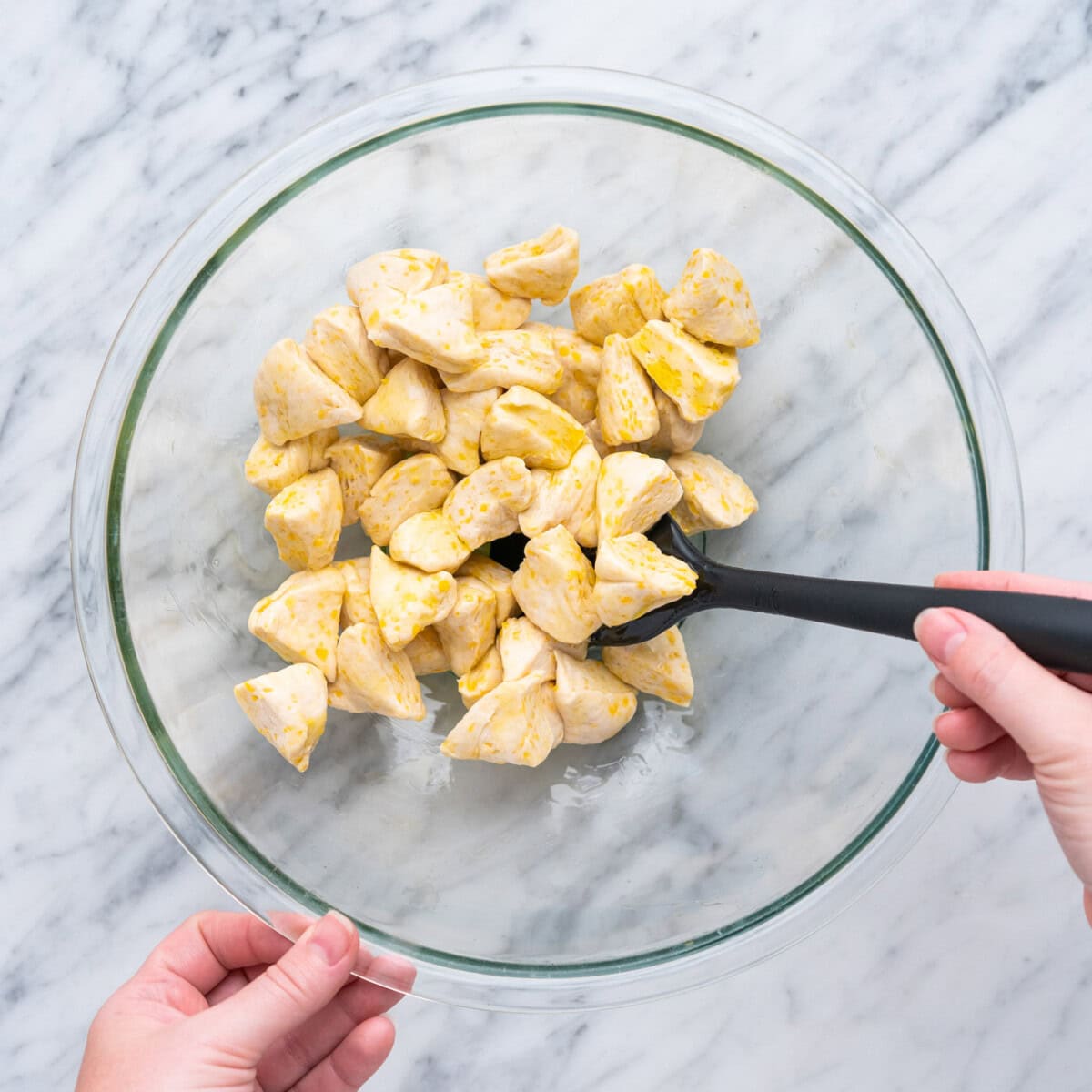 tossing chopped biscuit dough to olive oil in a bowl