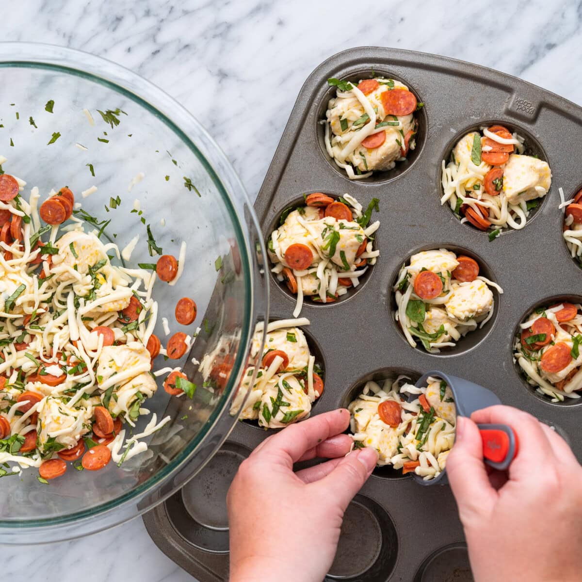 adding pizza bite ingredients to a muffin pan