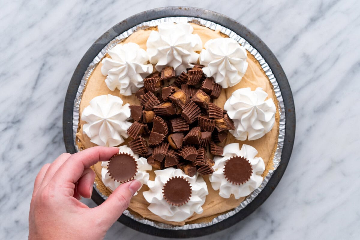 adding peanut butter cups on top of piped whipped cream rosettes