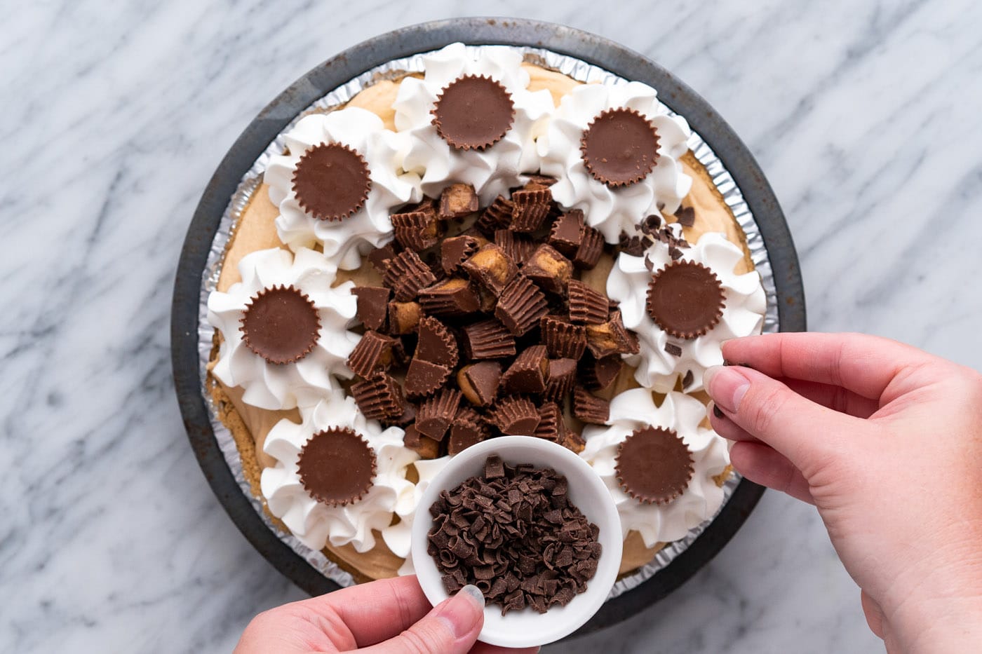 sprinkling shaved chocolate on top of Reese's pie