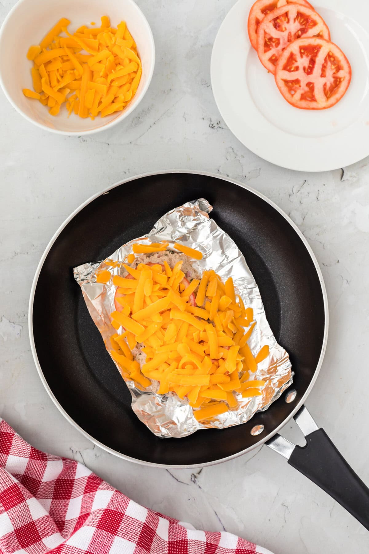 shredded cheddar cheese over tomato and tuna salad