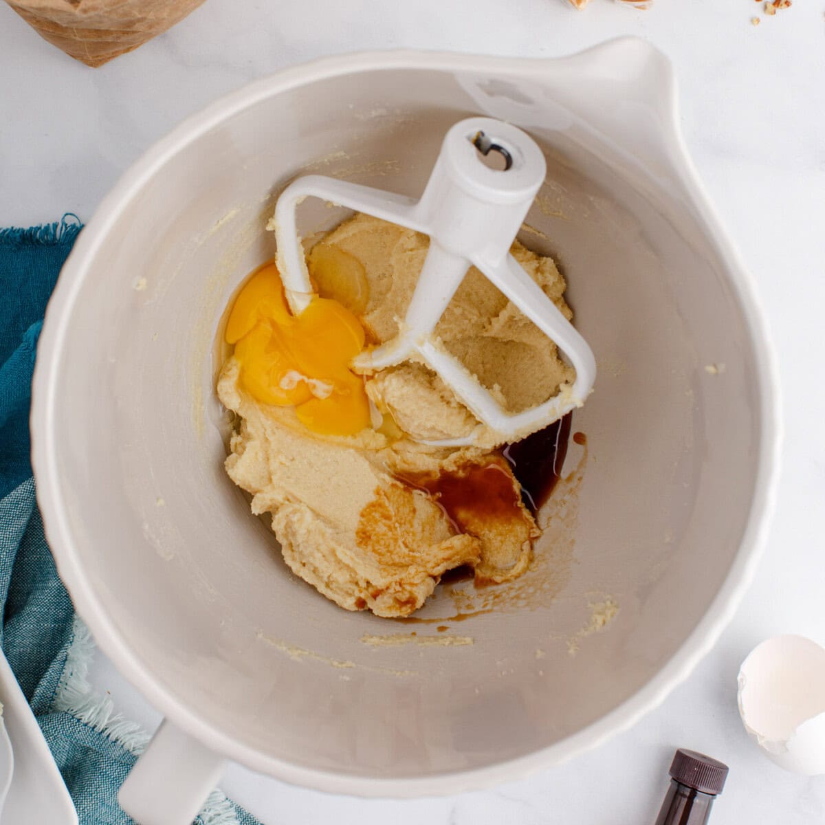eggs and vanilla added to a mixer bowl with butter and sugars