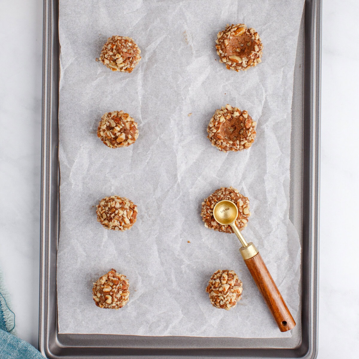 pressing turtle thumbprint cookies with a measuring spoon