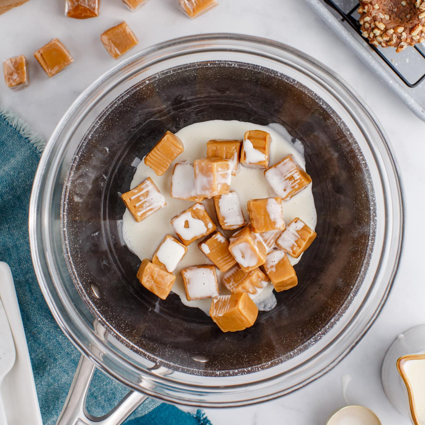 caramels and heavy cream in a bowl over a saucepan