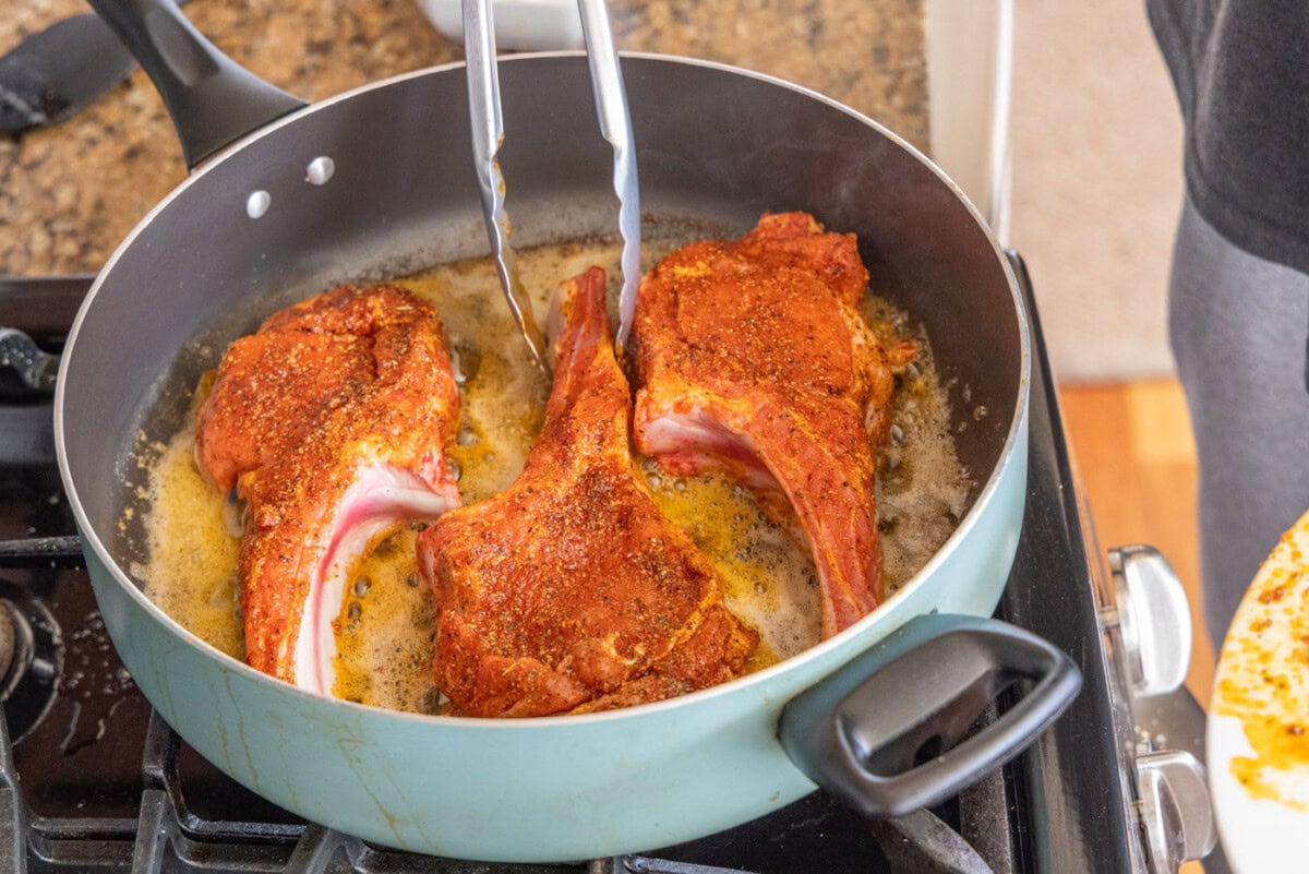 veal chops cooking in skillet