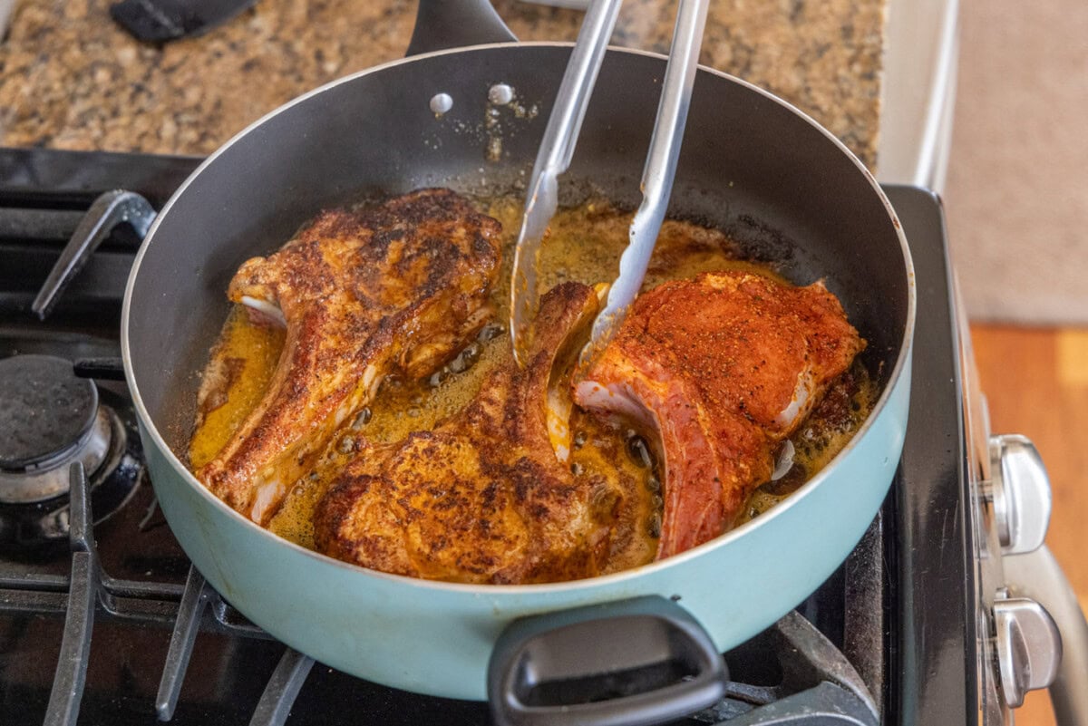 flipping veal chops in a skilet