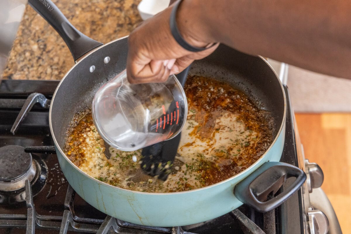 pouring lemon juice into skillet with juices