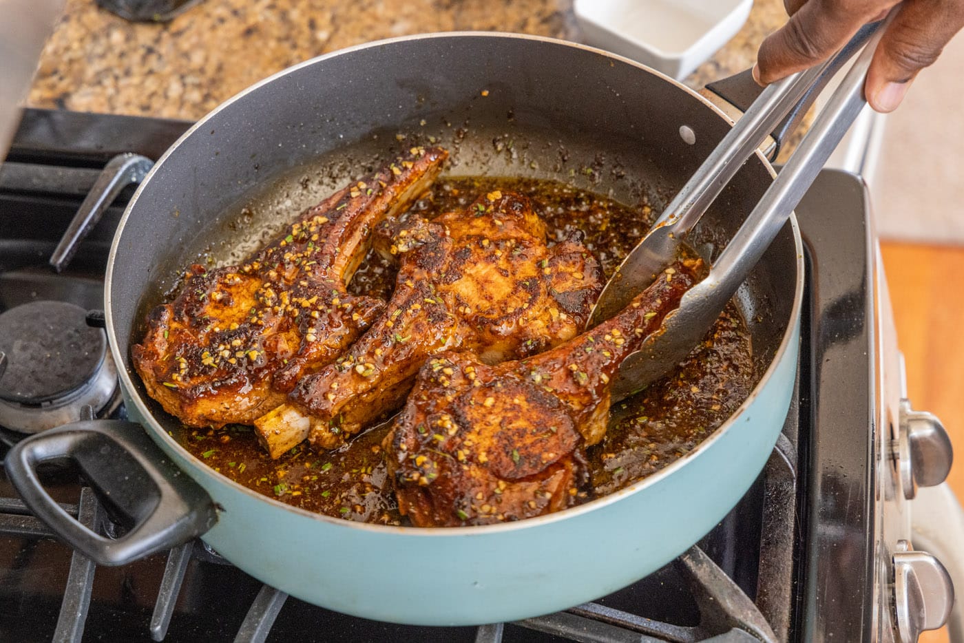 flipping veal chops in a skillet with tongs