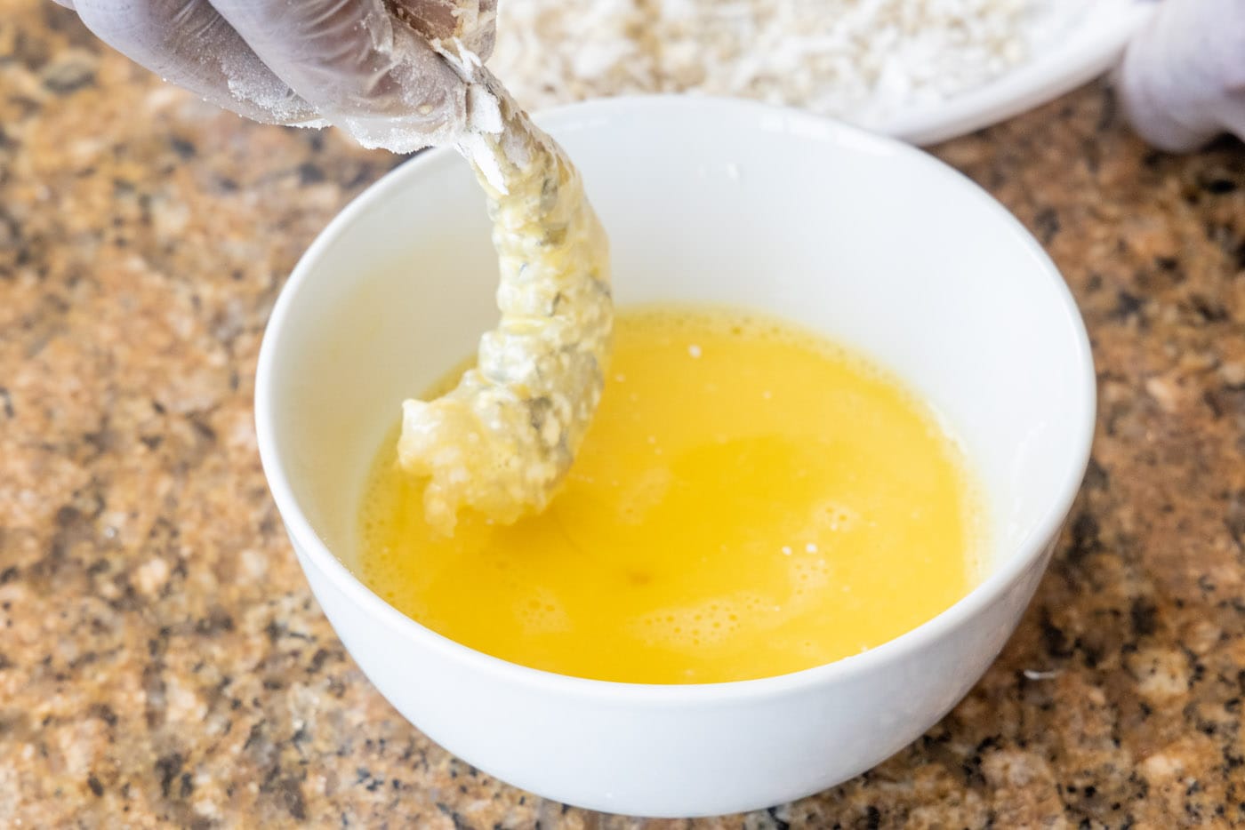 dipping flour dredged shrimp in egg