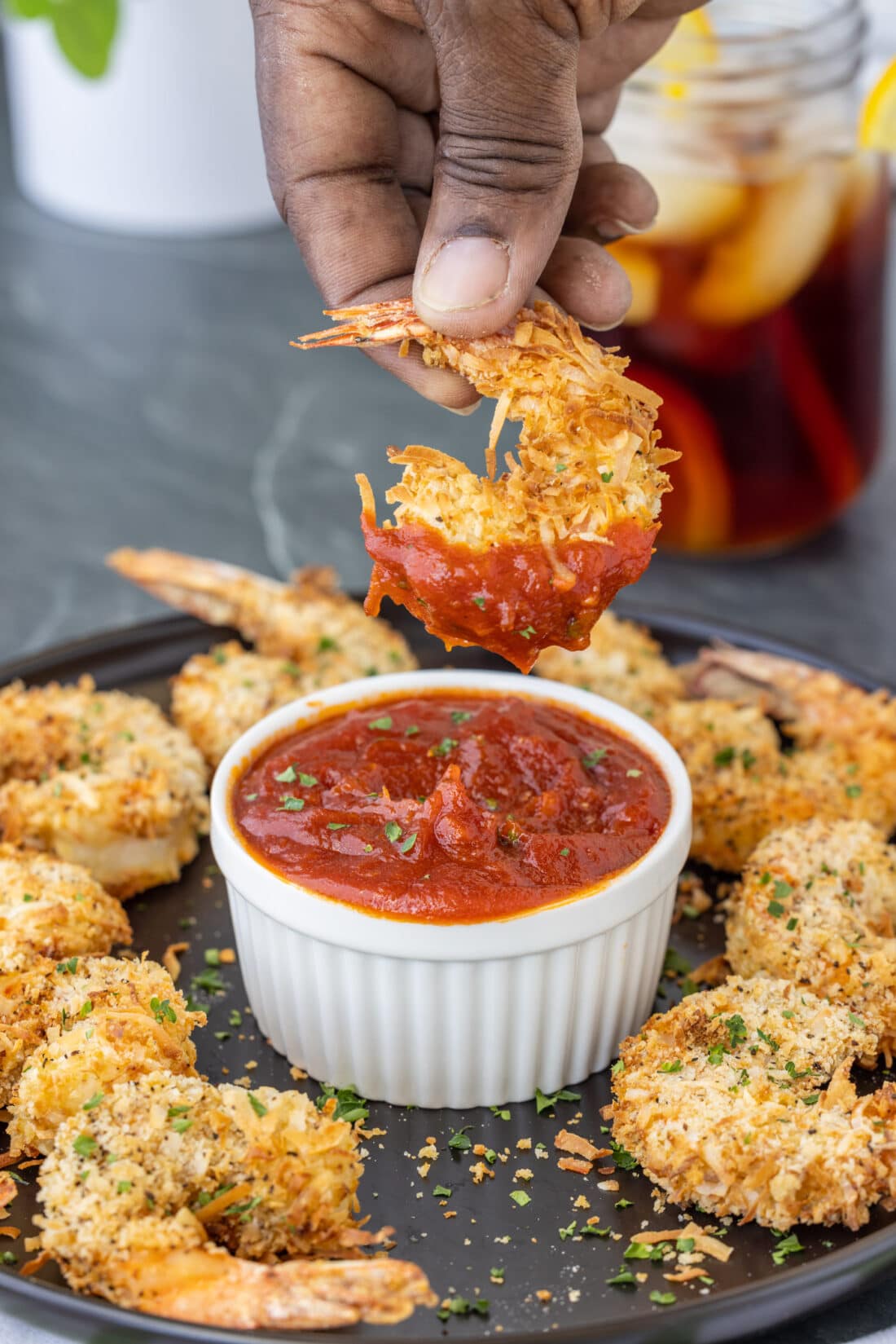 dipping Air Fryer Coconut Shrimp in cocktail sauce