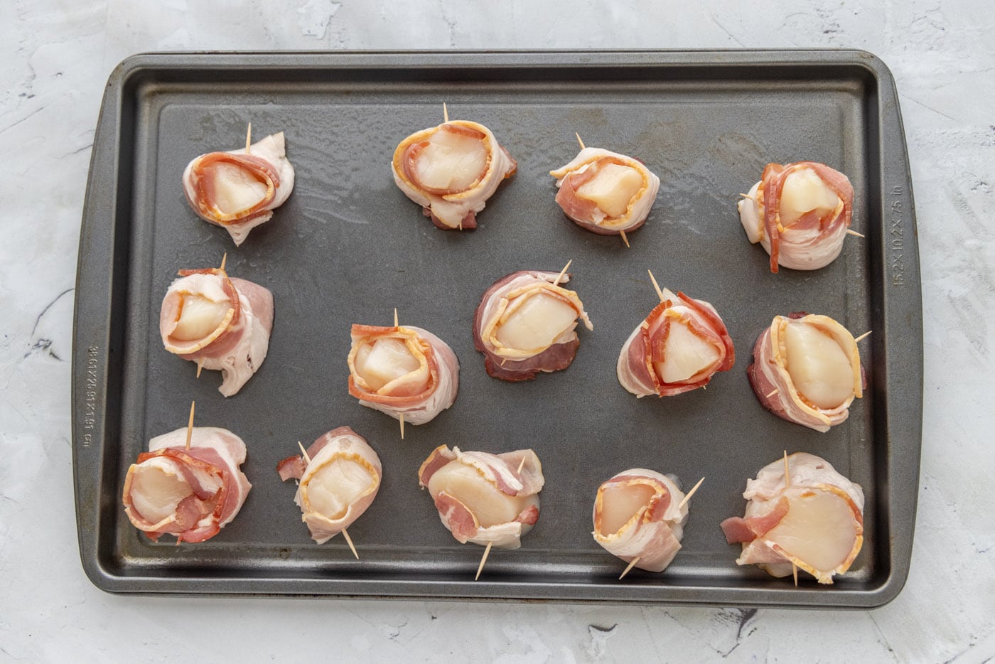 sea scallops wrapped in bacon on a baking shet